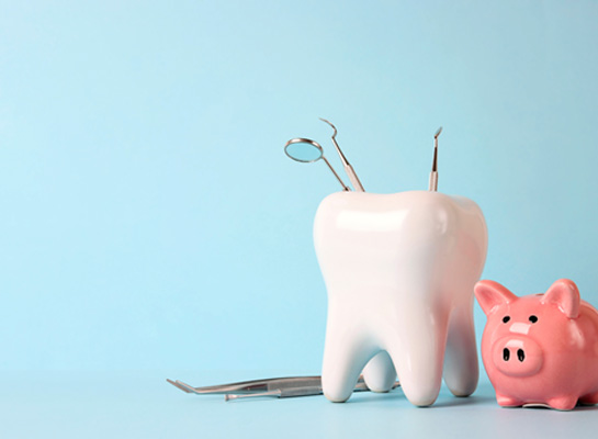 A large ceramic tool with dental instruments next to a pink piggy bank