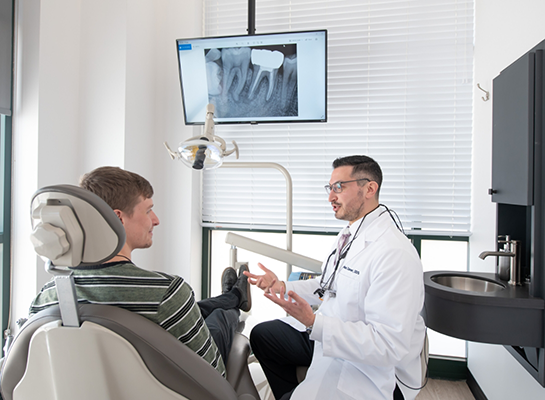 Dentist talking to young man in dental chair