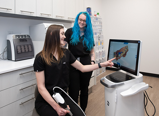 Two dental team members looking at screen with digital impressions of teeth