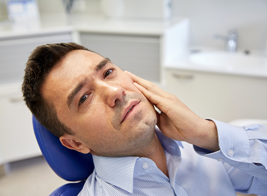 Man holding his cheek in pain while visiting emergency dentist