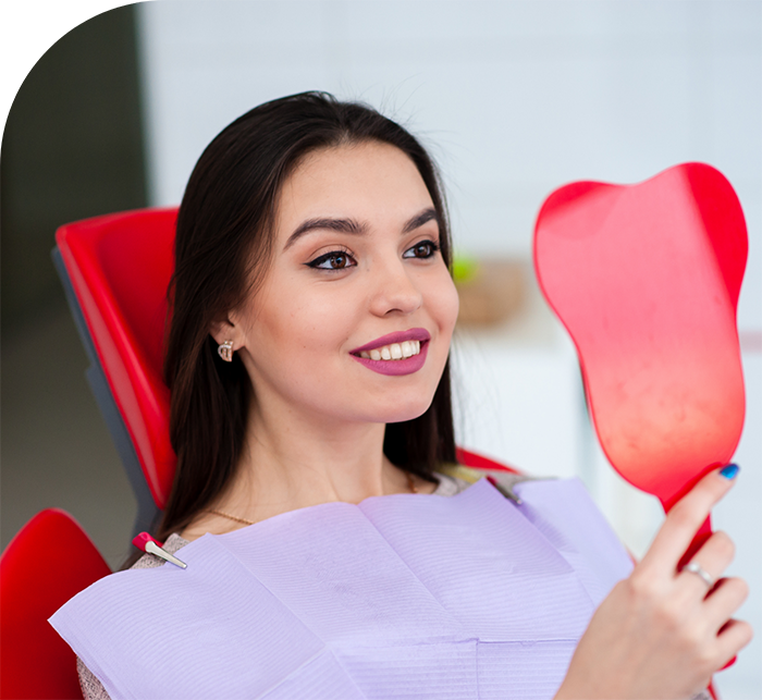 Woman in dental chair looking at her face after facial aesthetic services in White Marsh