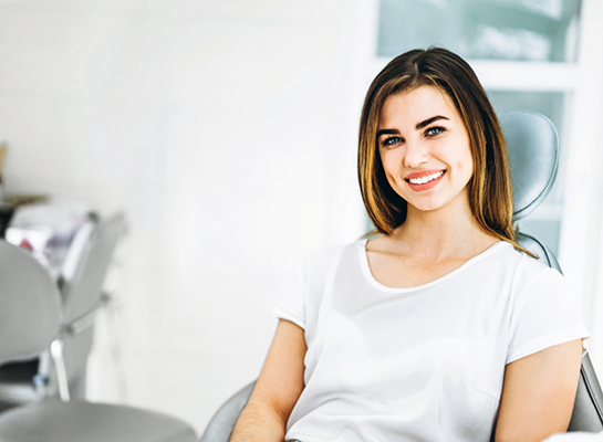 Woman in white tee shirt smiling in dental chair