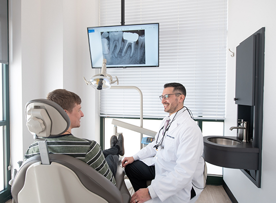 Young man in dental chair talking to dentist