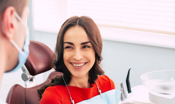 Woman in dental chair grinning at her dentist