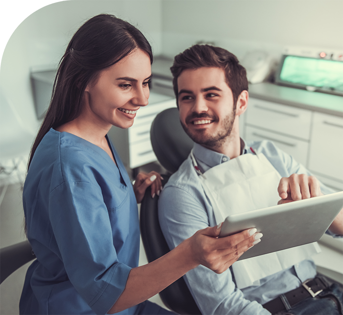 Dentist showing a patient a tablet after replacing missing teeth in White Marsh