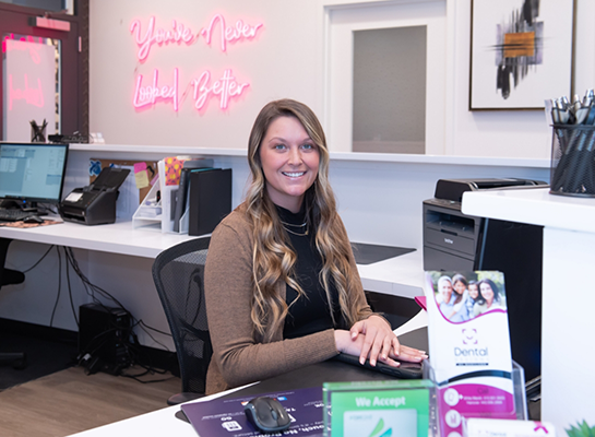 Smiling dental team member sitting at front desk