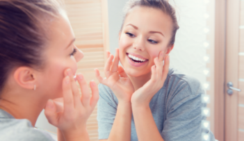 Young woman looking in mirror at her smile