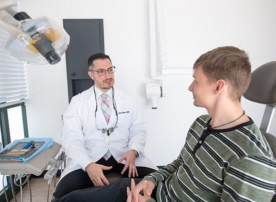 Dentist talking to young man in treatment chair