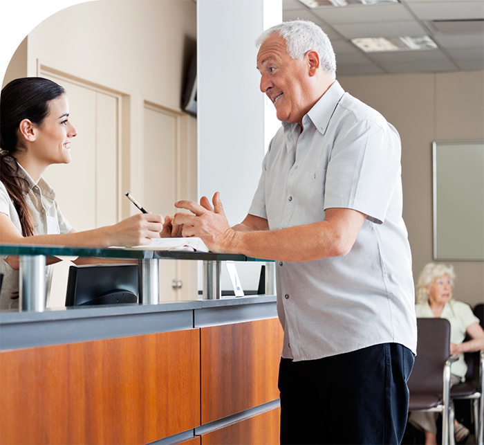 Senior man talking to receptionist in White Marsh dental office