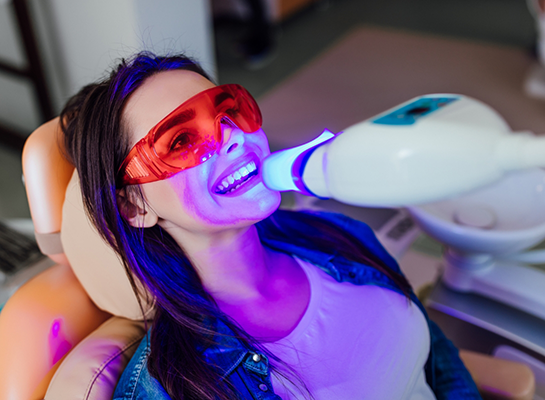 Woman in dental chair receiving professional teeth whitening