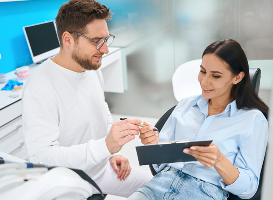Woman in dental chair signing off on forms