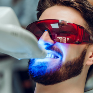 Man undergoing teeth whitening procedure in dental office